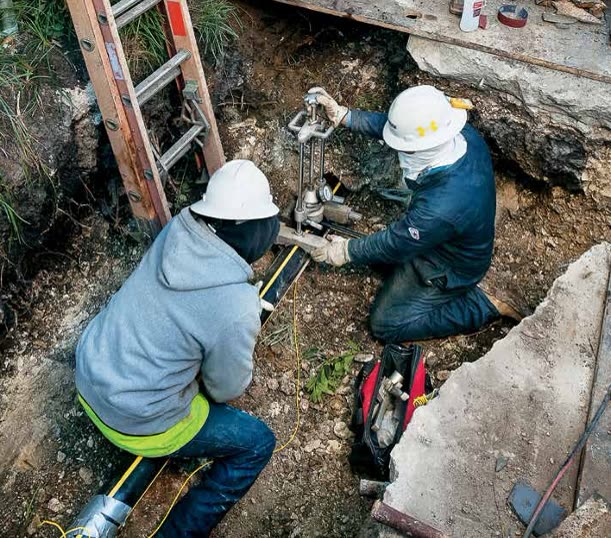Inspectors verifying a tapped gas service in an open excavation